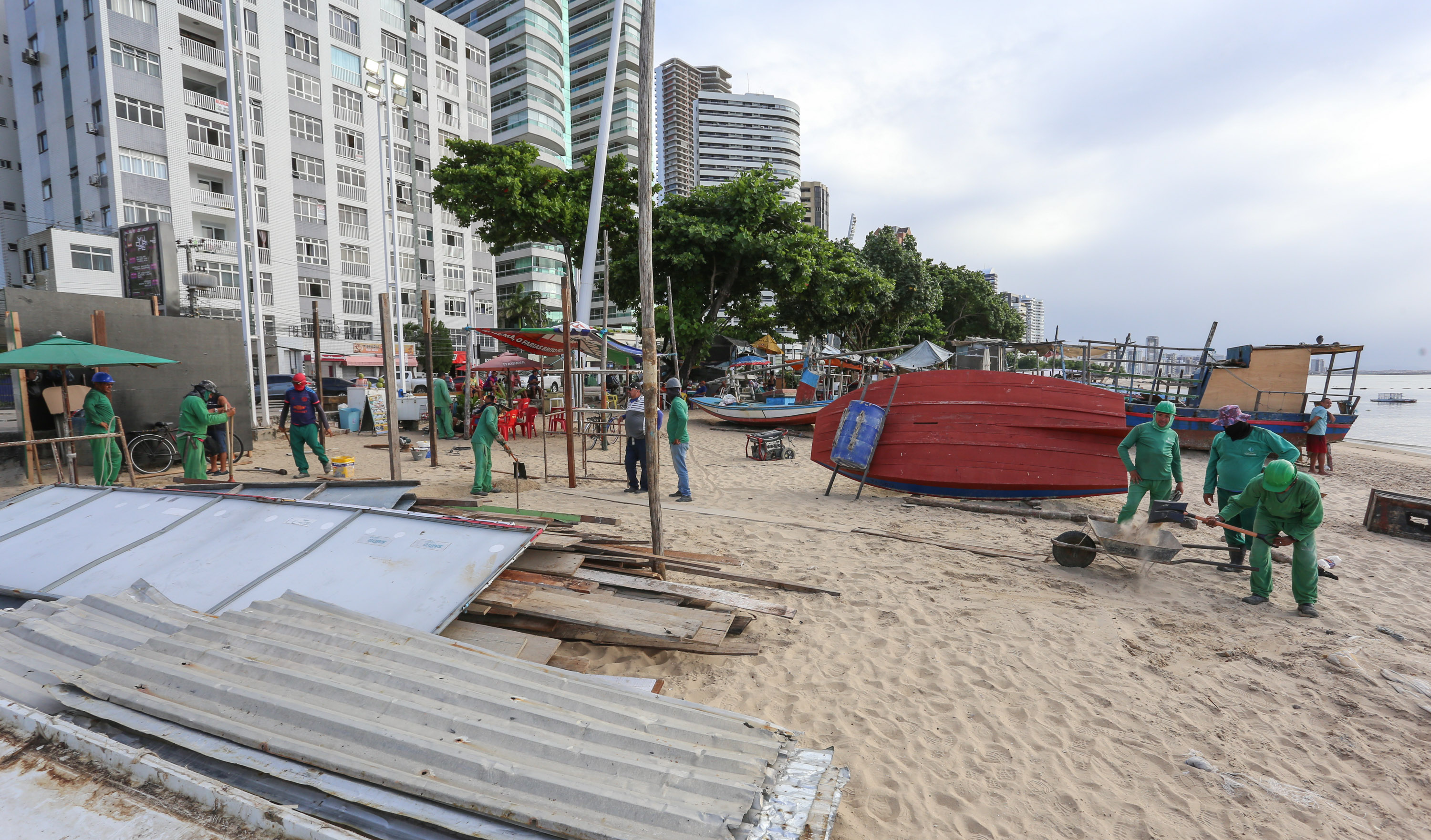 operários trabalhando na faixa de areia da beira-mar